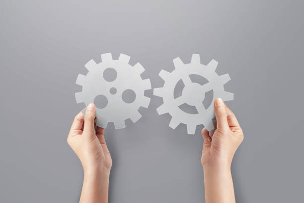 istock Two hands holding gear from at grey background. 1412157948