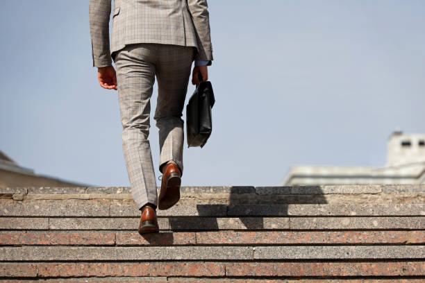 Man in a business suit with briefcase climbing stone stairs, male legs in motion on the steps stock photo