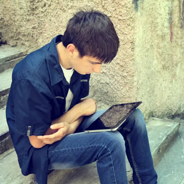 Toned Photo of Teenager with Tablet Computer on the Street