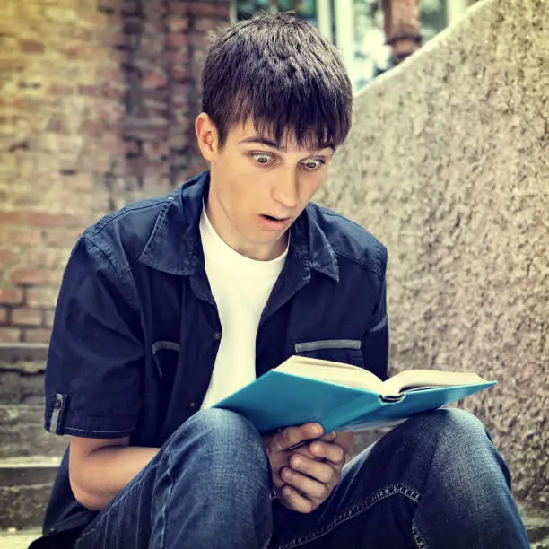 Toned Photo of Surprised Teenager with the Book on the City Street