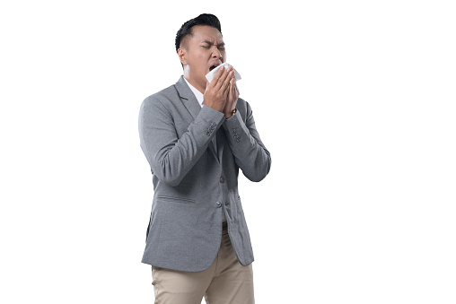 Indonesian Business Man on white Background abou to sneeze covering his face with tissue