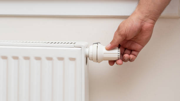 istock Man's hand adjusting the temperature of a radiator. 1412159707