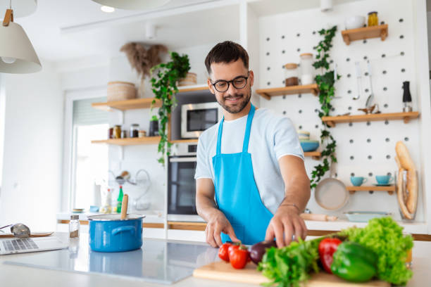 istock Handsome young man man stand at modern kitchen chop vegetables prepare fresh vegetable salad for dinner or lunch, young male cooking at home make breakfast follow healthy diet, vegetarian concept 1412160906
