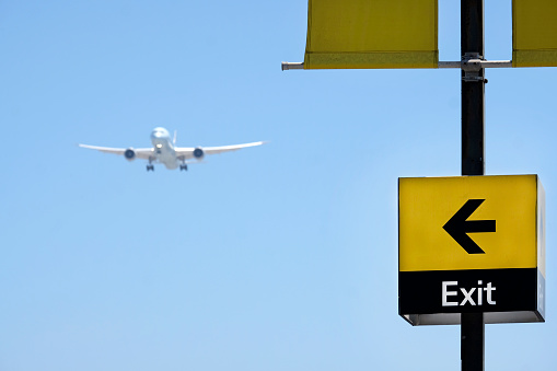 Approaching plane with a sign reading exit pointing at it against a blue sky