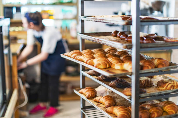 pão francês fresco e croissants em uma padaria em rack de resfriamento - bakery - fotografias e filmes do acervo