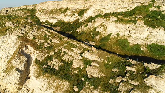 Aerial view of a rocky slope covered with green moss in a sunny summer day. Natural background, white mountain and green vegetation.