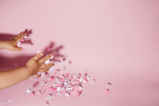 istock Falling confetti in child hands on bright pink background, copy space 1412164489