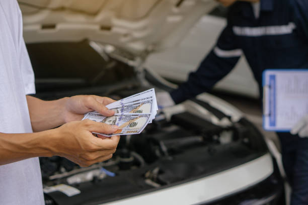istock Mechanic man takes cash as payment from customer.after finish checking car system.Professional service.checking the opened hood car.Repair service. 1412164536