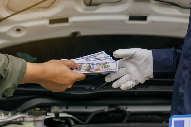 istock Mechanic man takes cash as payment from customer.after finish checking car system.Professional service.checking the opened hood car.Repair service. 1412164675