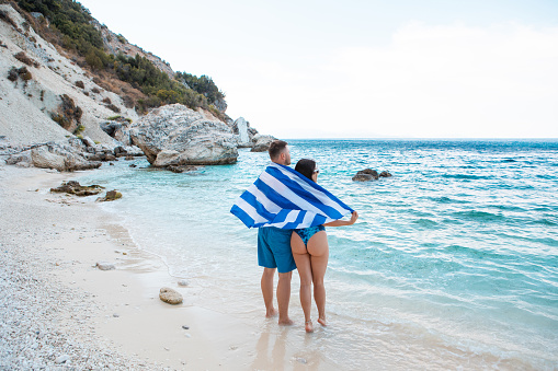 couple with greece flag at sea beach summer vacation
