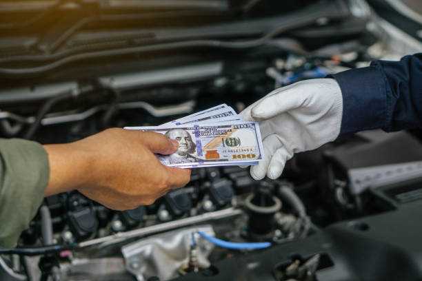 istock Mechanic man takes cash as payment from customer.after finish checking car system.Professional service.checking the opened hood car.Repair service. 1412164782