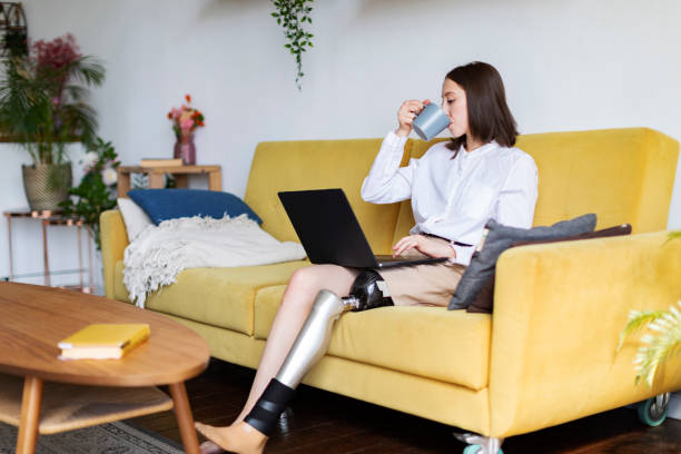 istock Young woman amputee with prosthesis using laptop at home 1412166696