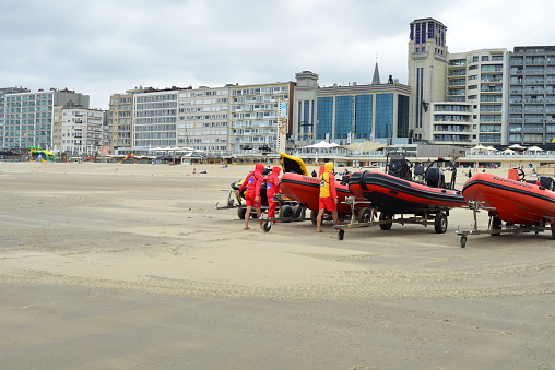 Blankenberge, West-Flanders Belgium - July 31, 2022: lifeguards with red jackets and red motor speed boats on beach leaving, bad weather for swimming and sunbathing
