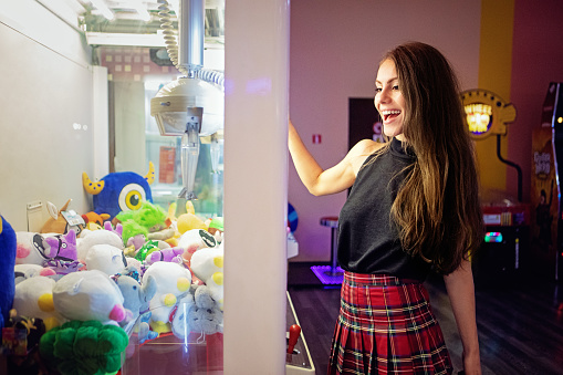 Portrait of young woman playing with toy claw machine