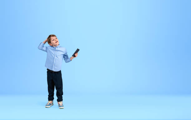 istock Boy with phone in hand, dreaming on light blue background. Copy 1412176346