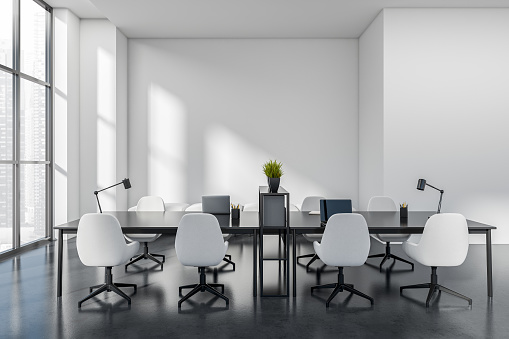White coworking interior with armchairs and laptop computer on table, dark concrete floor. Workplace with panoramic window on Singapore city view. 3D rendering