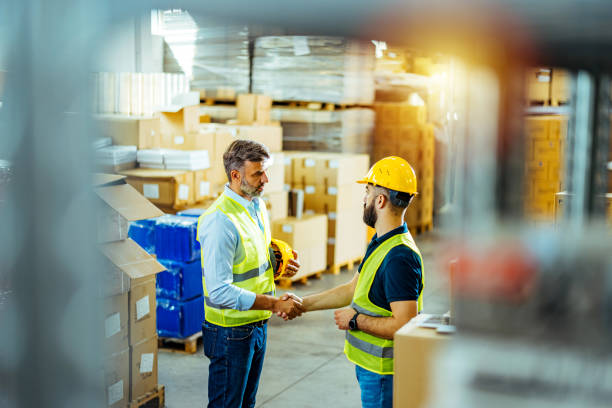 istock Serious businessman having a handshake with warehouse worker in logistics warehouse 1412177365