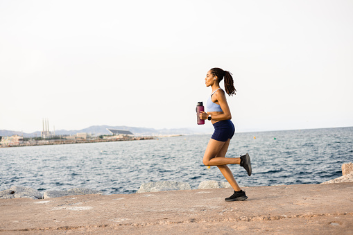 Young African American woman jogging on the beach