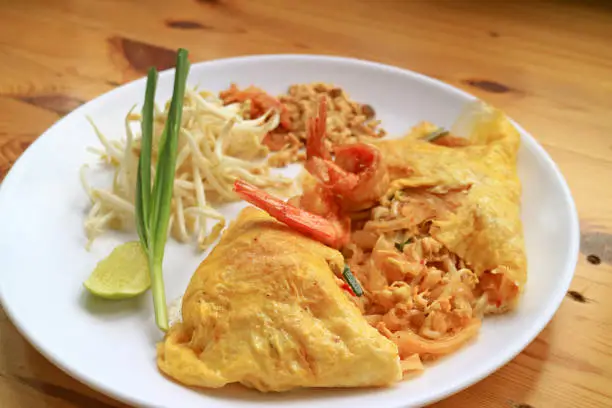 Photo of Plate of Pad Thai, Flavorful Thai Style Fried Noodle Wrapped in Fried Egg and Topped with Prawns
