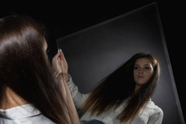 istock Young woman looking at her reflection in the mirror. 1412182780