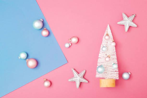 istock Minimalistic Christmas and New Year art composition. Miniature white spruce tree on pink and blue pastel background with Christmas balls. 1412183852