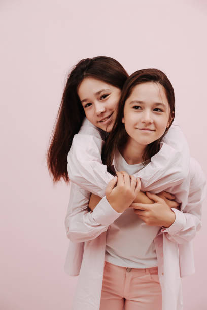 istock Friendly affectionate twin girls. One is hugging other from behind. 1412183969