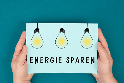 Save energy is standing in german language on the paper, light bulbs, increase of electricity and gas costs, regulations for the winter, sanctions against russia