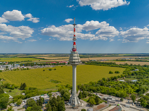 Drone point of view of TV tower in Dobrich, Bulgaria, agricultural fields, blue sky and cloudscape  (Bulgarian:Телевизионната кула, град Добрич, България).The scene is situated in Dobrich, Bulgaria and is taken with DJI qudracopter Mavic III