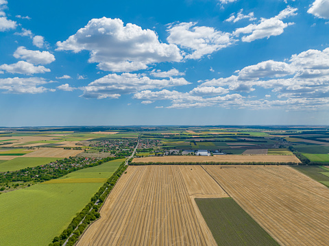 Wide dron shot of agricultural fields near Dobrich, Bulgaria, blue sky and cloudscape. (Bulgarian: Град Добрич, България)The scene is situated in Dobrich, Bulgaria and is taken with DJI qudracopter Mavic III