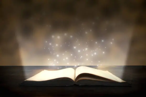 Magic book with a beam of bright light and sparks. An open book on the table. Knowledge book - learning concept.