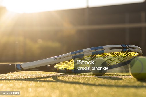 istock Tennis balls and racket on the grass court 1412188048