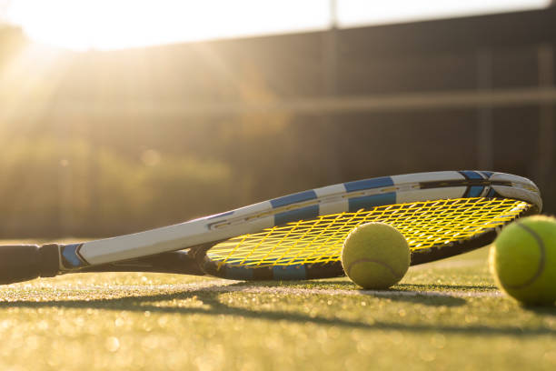 Tennis balls and racket on the grass court stock photo
