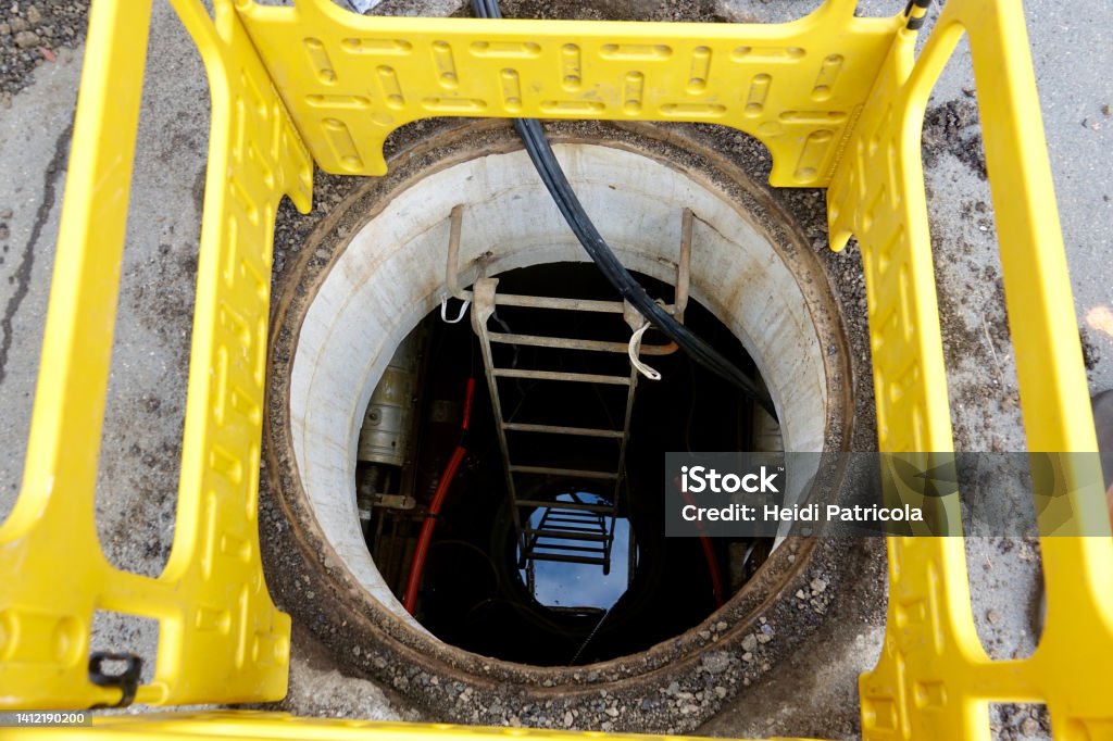 Safety barrier around an open manhole in the street Manhole Stock Photo