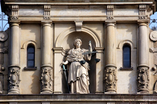Justitia, Lady Justice, standing with scale and sword on the facade of the Strafjustiz Gebäude (criminal justice building) in Hamburg, Germany.