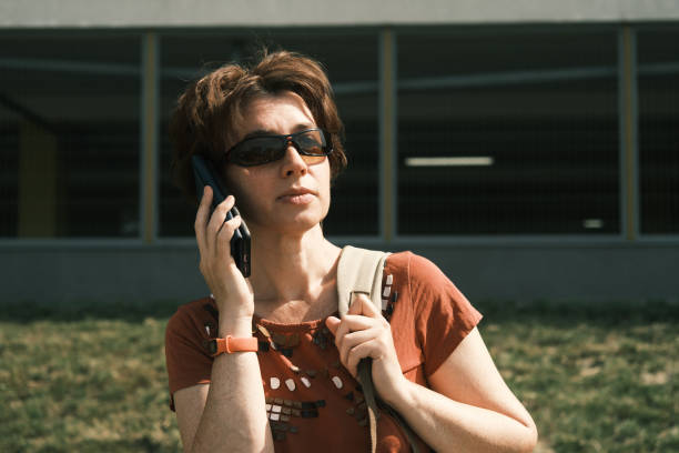 Mature woman is talking by phone in city