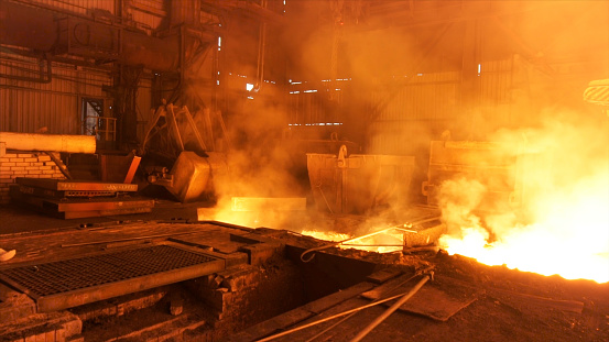 Hot shop at the metallurgical factory with molten steel in the chute. Metallurgical works, industrial process, iron production.
