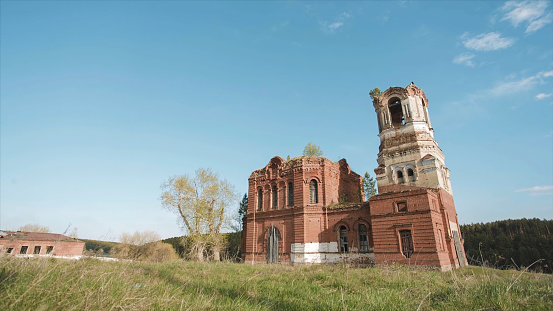 Beautiful scenic view of ancient Buddhist Temple at the background of field. Video. Ancient ruined Russian church or temple overgrown with grass among field.