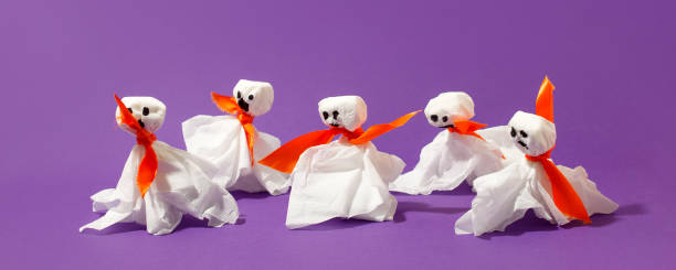 istock Halloween paper decorations on bright purple violet background. Black  ghosts from paper napkins. Halloween concept. Flat lay, top view, overhead. Party greeting card, invitation, flyer, banner 1412196289