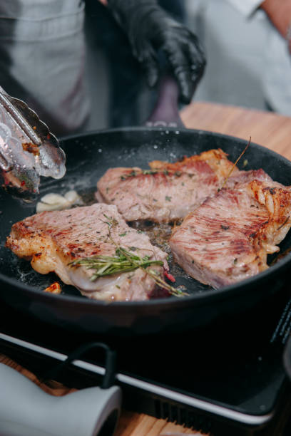 cooking steaks in a pan. cooking beef at the culinary master class. the hands of the chef in black gloves. - fine dining grilled spring onion healthy lifestyle imagens e fotografias de stock