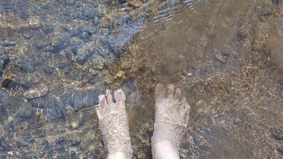 woman's feet soak in the clear river