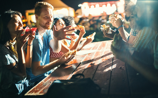 Closeup side view of group of young adults having a snack on a night out.