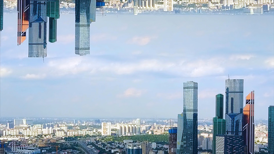 Panoramic aerial view of skyscrapers in the financial district, England, United Kingdom, mirror horizon effect. Modern tall buildings on cloudy sky background, inception theme.