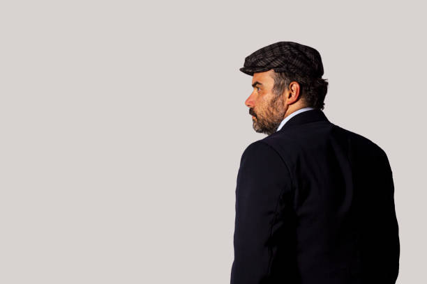 istock Businessman looking aside wearing a suit and a flat cap 1412197718
