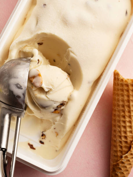 ice cream, ice cream with ice cream cone, i̇ce cream with almonds, i̇ce cream in a spoon, metal scoop scrapes ice cream from the box - gelato imagens e fotografias de stock