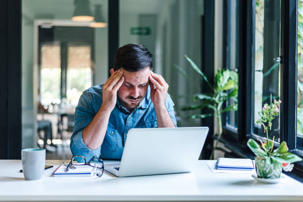 istock Stressed businessman working on laptop while sitting at home office. 1412200218