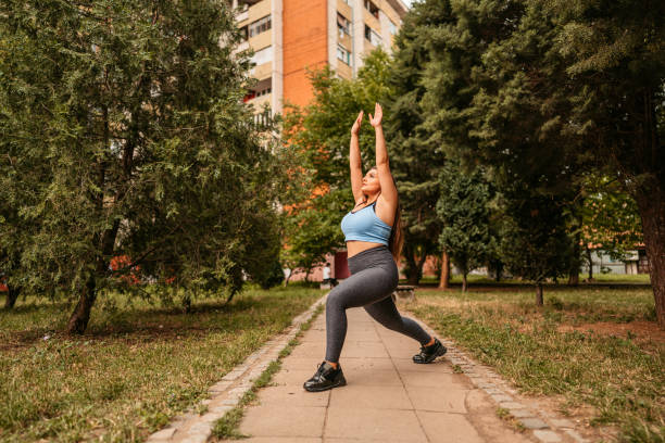 mujer joven haciendo estocadas en un parque - lunge fotografías e imágenes de stock