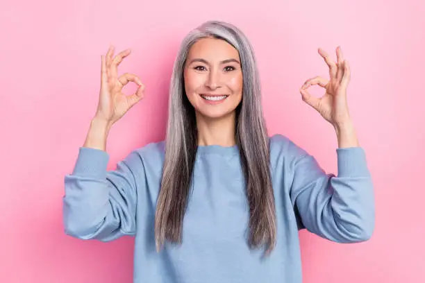Photo of pretty cute lady pensioner dressed blue pullover showing two okey signs isolated pink color background.