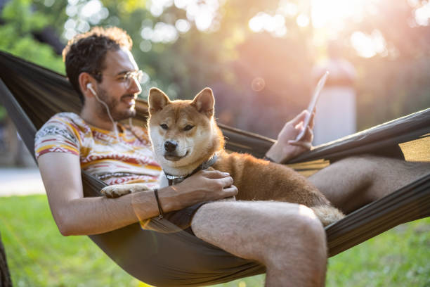 istock Man relaxing with his dog in the park and reading e-book 1412203502