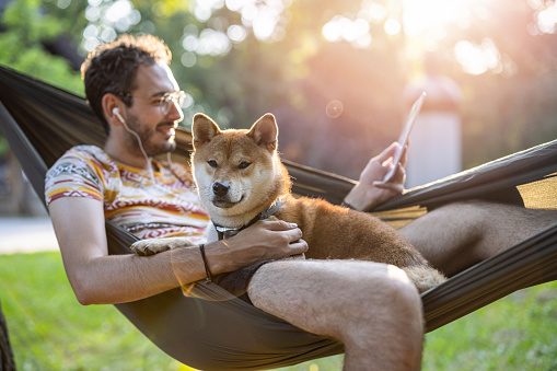 Young man and his Shiba Inu dog relaxing in the park
