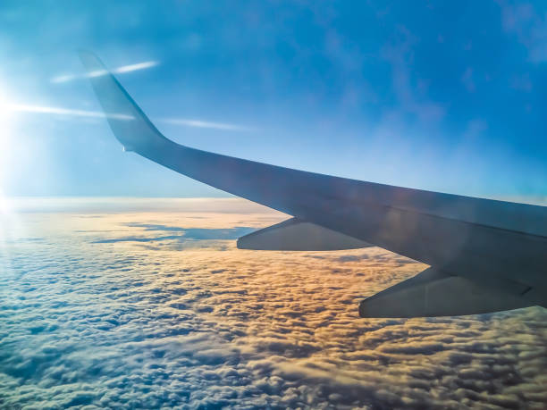 istock Airplane wing over white clouds in the rays of the rising sun 1412204731